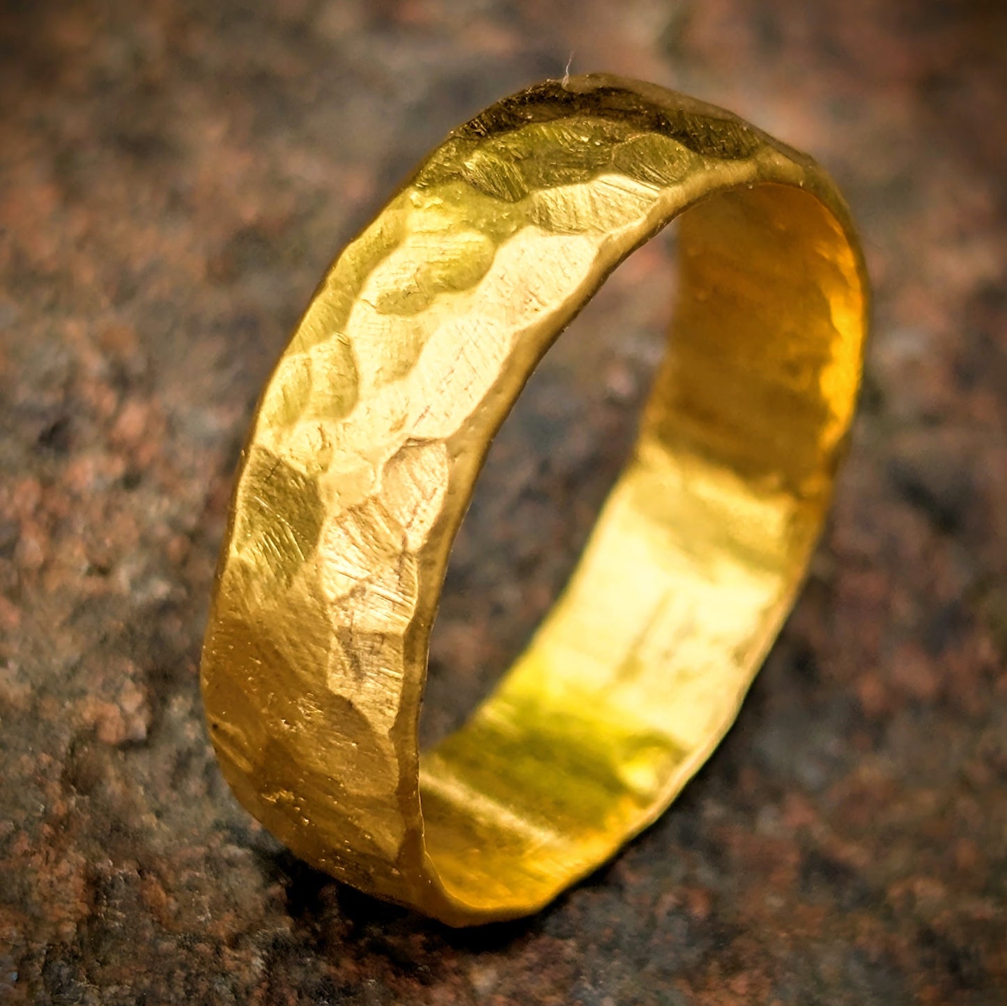 Gold ring with a textured surface on a brown background